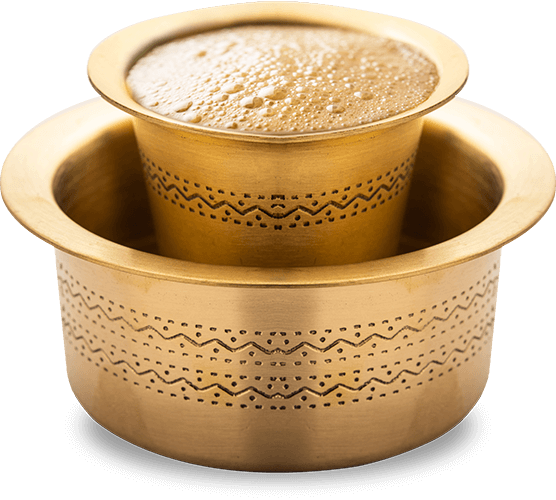 Image of South Indian filter coffee served in a traditional brass davara set, featuring a frothy top and rich, aromatic brew